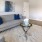 Spacious and well lit living room with wood floors and a large window with access to the kitchen